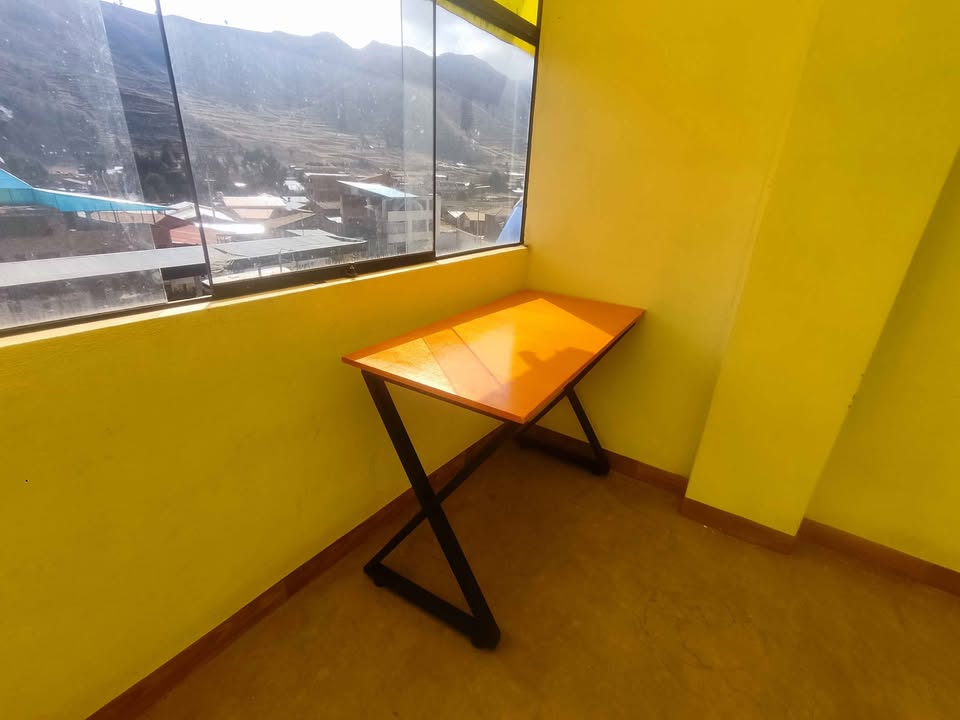 Escritorio industrial ubicado junto a una ventana en una habitación amarilla