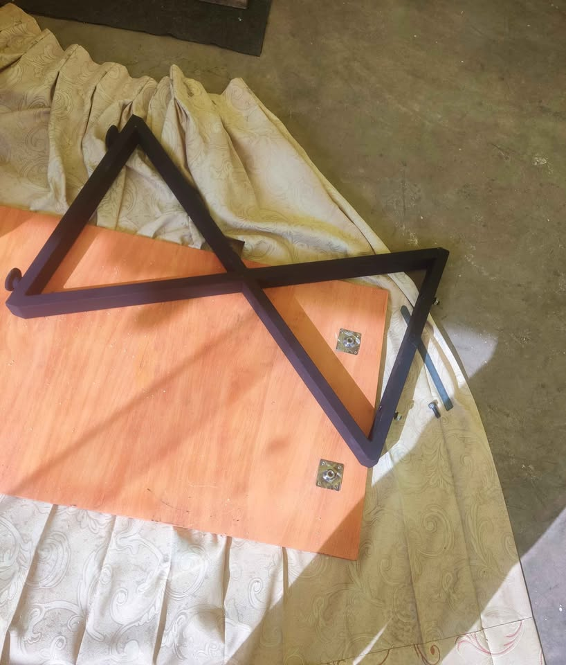 Tablero y dos patas de acero del escritorio separados para mostrar su diseño desmontable y sus pernos